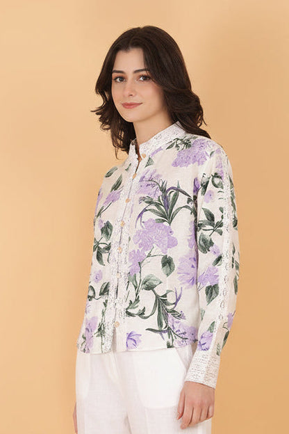 Woman wearing a floral blouse and white shorts against a beige background