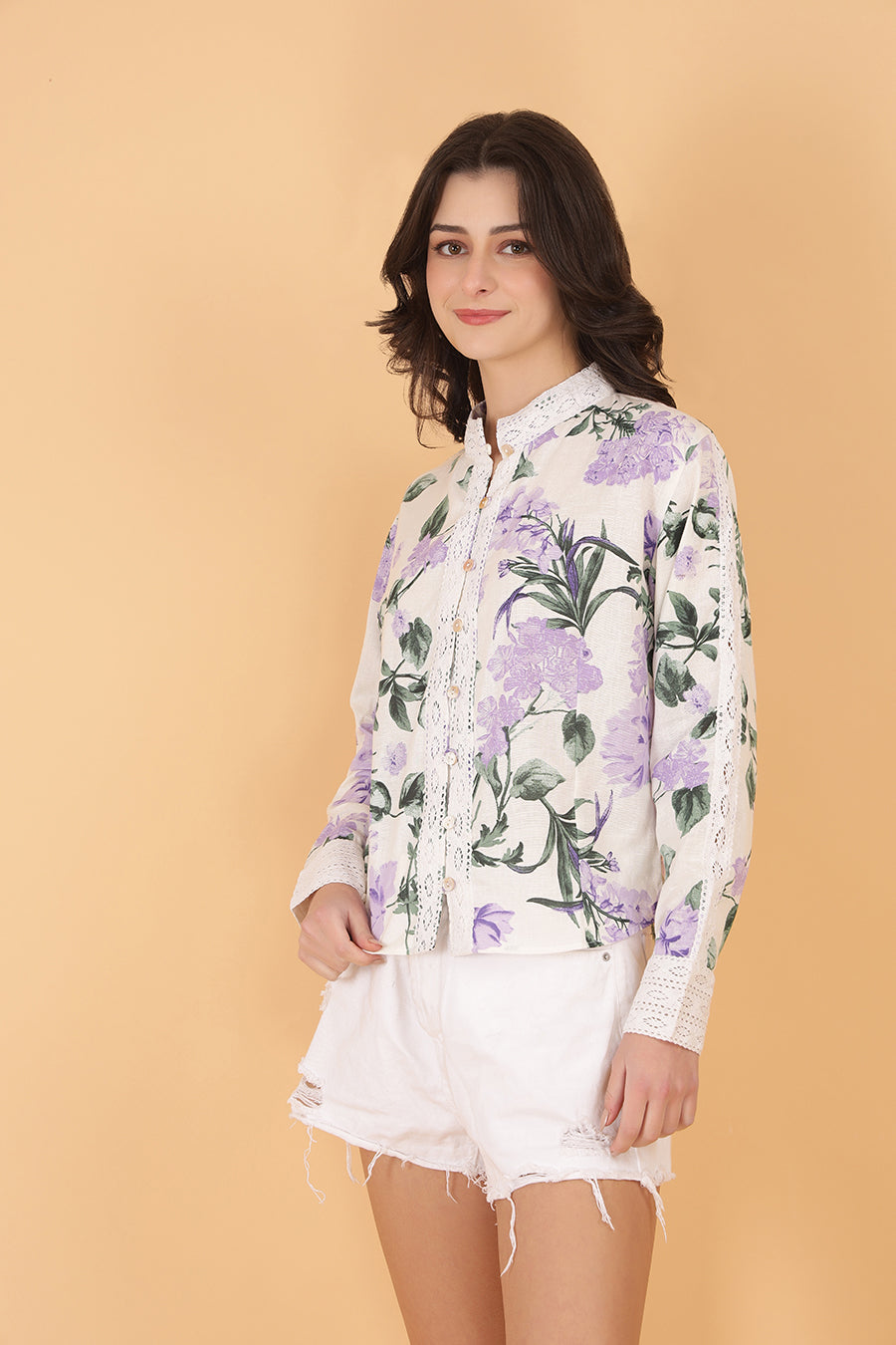 Woman wearing a floral blouse and white shorts against a beige background